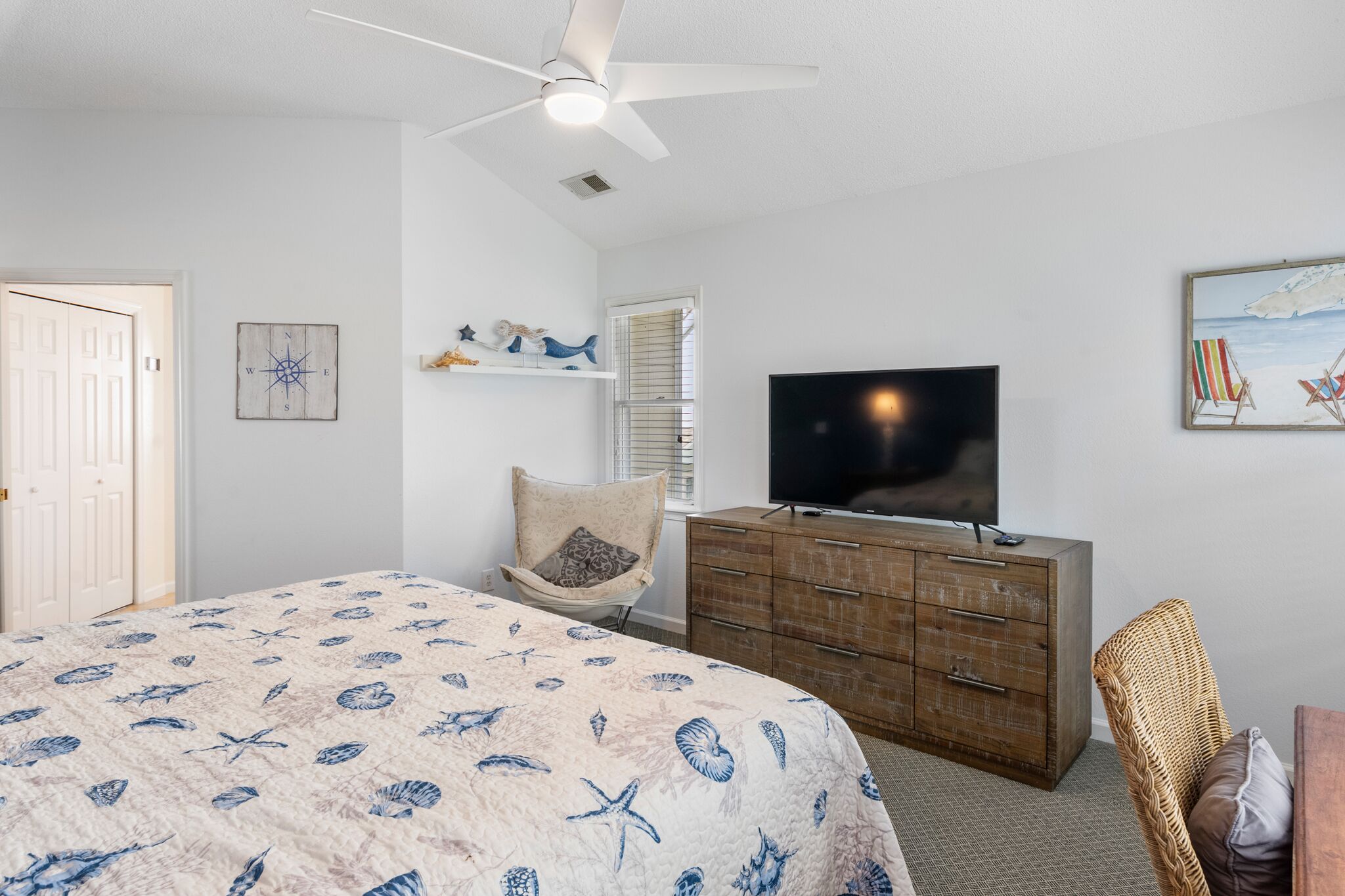 A bedroom with a bed, a TV, a dresser, and a chair.
