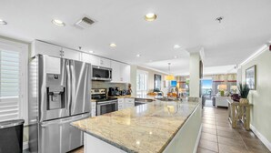 Cocina moderna con electrodomésticos de acero inoxidable, encimera de granito y vista al área de estar.