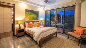 A bedroom with a bed, two bedside lamps, a nightstand, a chair, a large window, and a ceiling fan. - 7 bedrooms Manuel Antonio and Ocean view Private Pool and rooftop Jacuzzi (Puntarenas Province)