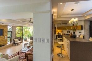 Una sala de estar moderna con un ventanal grande, un comedor y una cocina con barra.