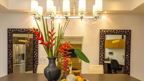 A dining area with a table set for two, a vase with red flowers, and a plate of fruit. - 7 bedrooms Manuel Antonio and Ocean view Private Pool and rooftop Jacuzzi (Puntarenas Province)