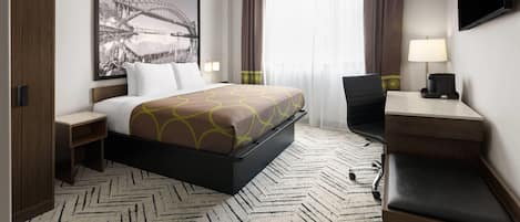 Habitación de hotel con cama, escritorio, silla y un cuadro grande en la pared.