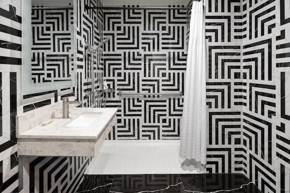 Une salle de bain avec un mur orné d’un motif géométrique, un lavabo et un rideau de douche.