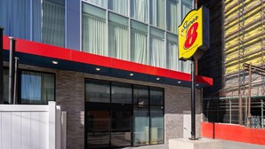 Ein modernes Gebäude mit großem Glasfront, einer Fassade in Rot und Blau und einem Schild für 'Super 8 by Wyndham'.