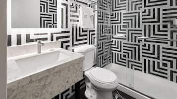 A bathroom with a white sink, toilet, and shower. The walls have a black and white geometric pattern.