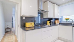 A modern kitchen with white cabinets, a black countertop, and a yellow toaster. - Henry Bell 2 bed in Helensburgh Near Loch Lomond (Helensburgh)