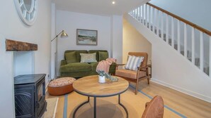 A living room with a sofa, armchair, round table, and a fireplace. - Henry Bell 2 bed in Helensburgh Near Loch Lomond (Helensburgh)