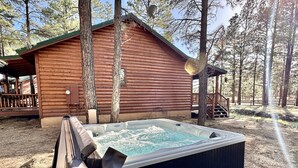 A hot tub in front of a wooden cabin with a deck, surrounded by trees. - The Prancing Pony | Hot Tub & Quiet Location! (Overgaard)