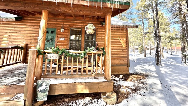 A log cabin with a porch decorated with greenery, a green door, and a sign with the number 2640. - The Prancing Pony | Hot Tub & Quiet Location! (Overgaard)