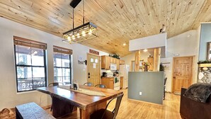 A spacious kitchen with wooden cabinets, a central island, and a hanging light fixture. - The Prancing Pony | Hot Tub & Quiet Location! (Overgaard)