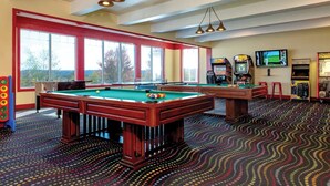 A pool table with a colorful dot-patterned carpet, a billiards table, and a television screen displaying a golf game. - Wyndham Vacation Resort! Serene · Clean · Fun! (Branson)
