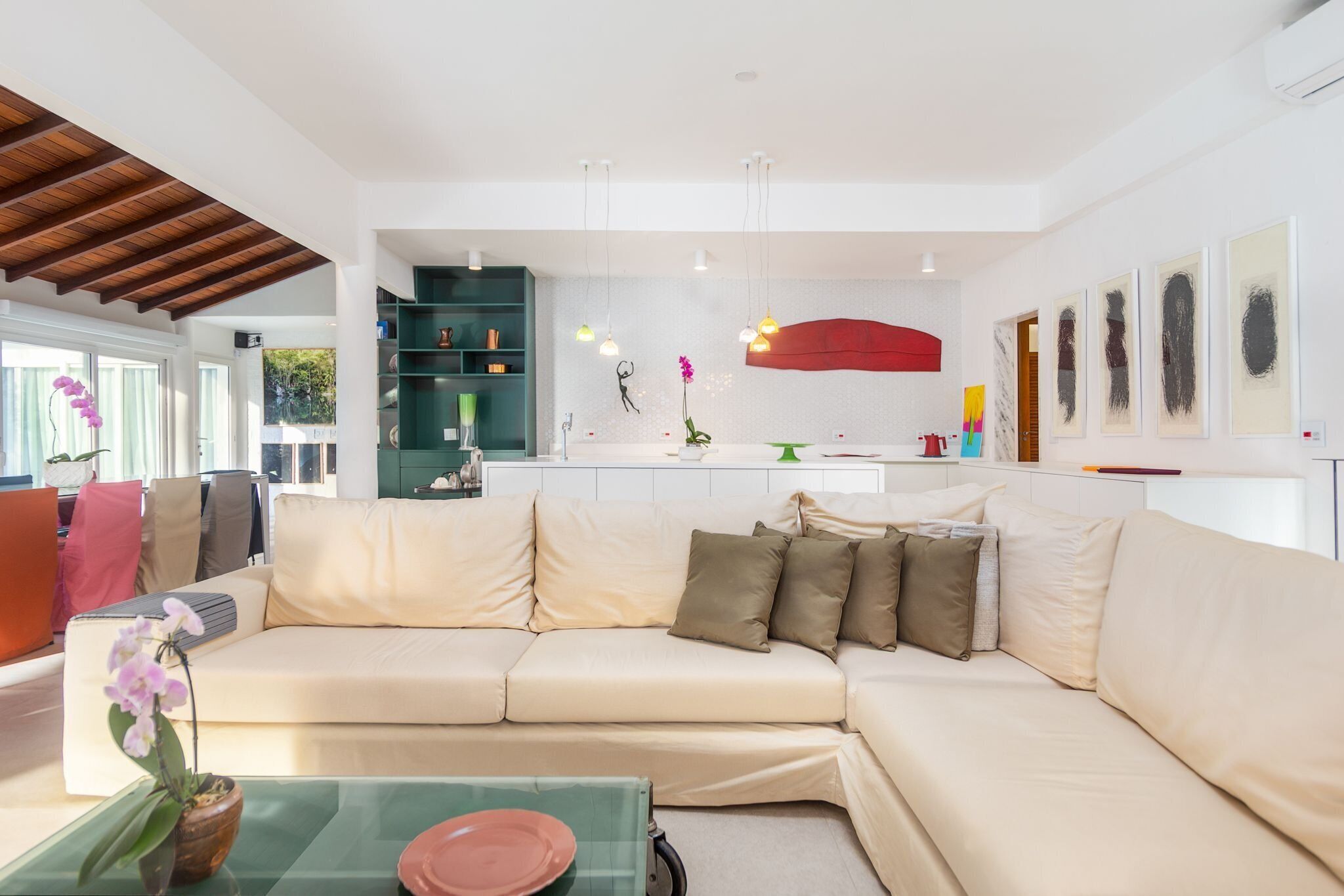 A modern living room with a beige sofa, a glass coffee table, and a kitchen area in the background.