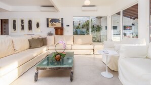 Un salon moderne avec un canapé, une table basse en verre et une petite table d’appoint.