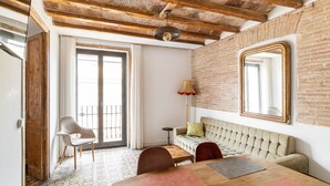 Una habitación con vigas de madera a la vista, un espejo grande, un sofá, una silla y un suelo con diseño.