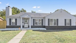 A single-story house with a front porch, a chimney, and a small front yard.