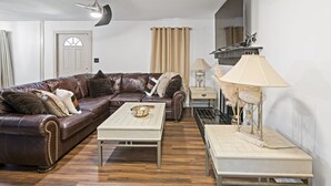 A living room with a brown leather sofa, a white coffee table, a lamp, and a mirror on the wall.