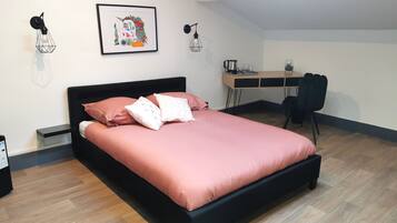 A modern bedroom with a black bed frame, pink bedding, and a desk with a chair.