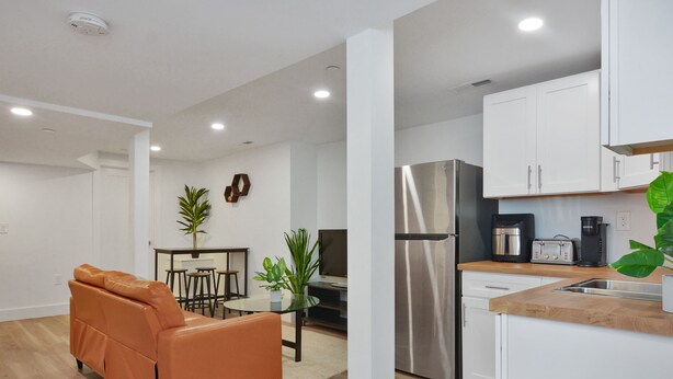 A modern kitchen with white cabinets, stainless steel appliances, and a wooden countertop. - Sleek Somerville Apartment near Encore! (Somerville)