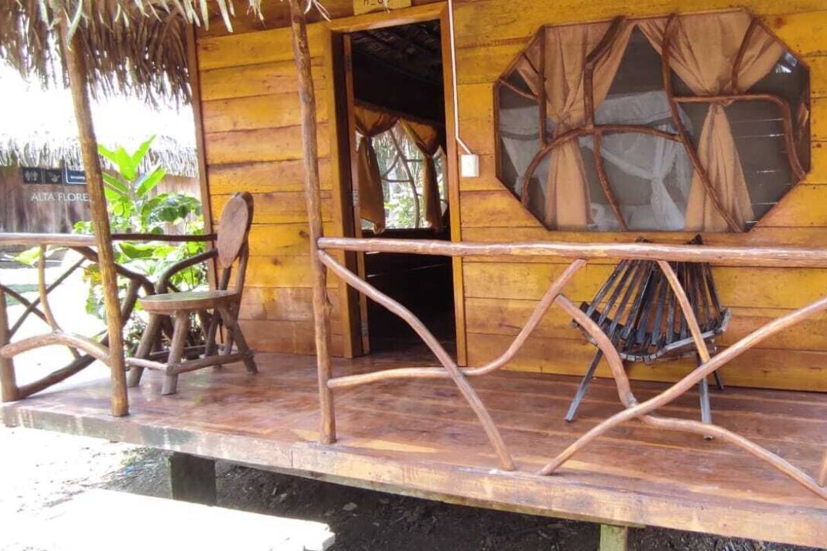 A wooden structure with a thatched roof, a wooden bench, and a hammock.