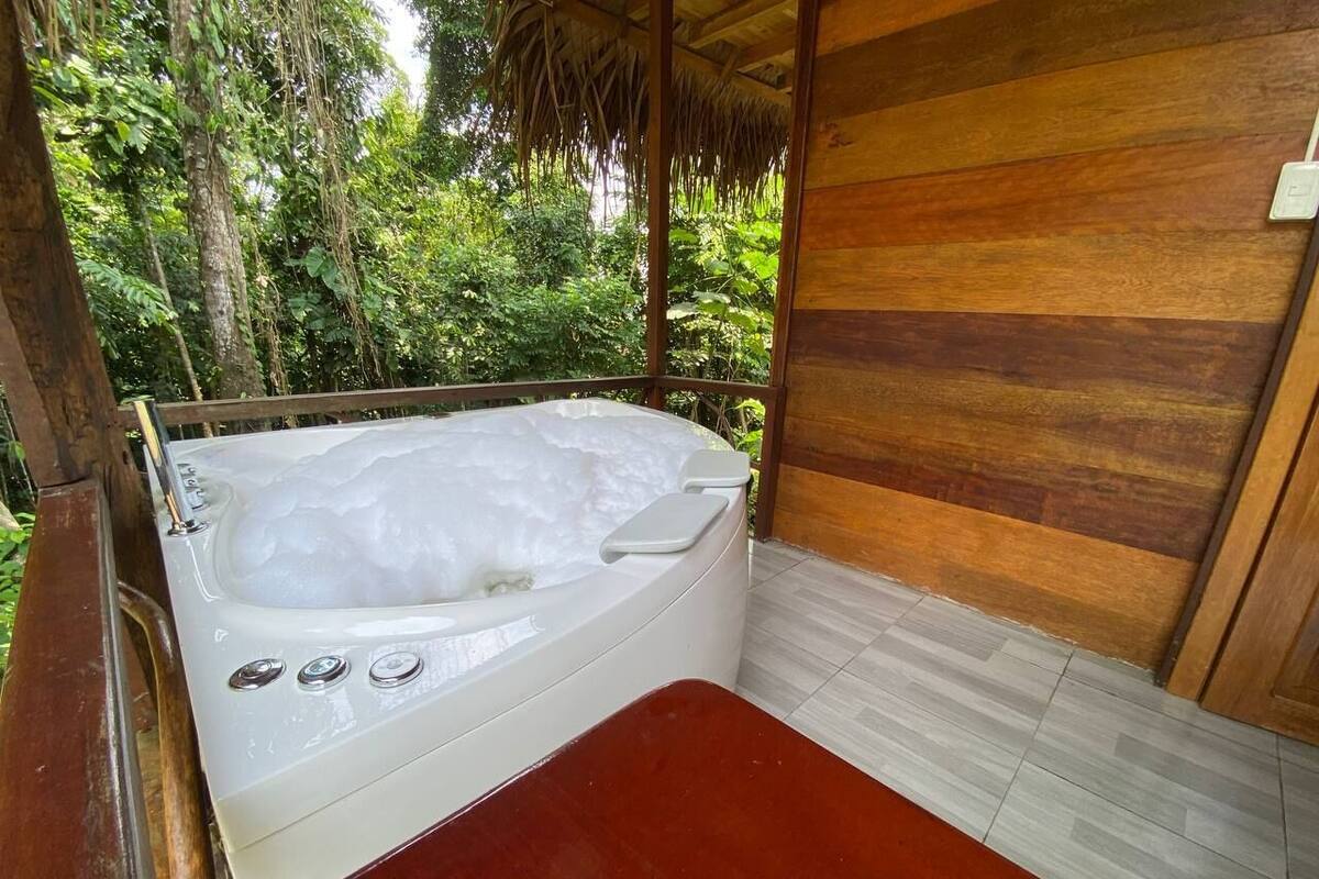 A hot tub in a wooden cabin with a view of lush greenery.