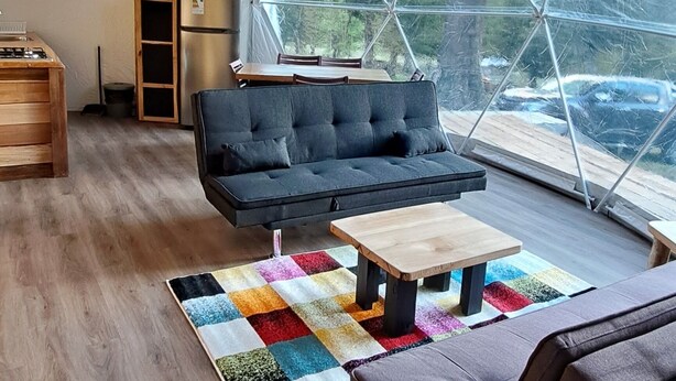 A spacious tent with a modern interior, including a sofa, a coffee table, and a dining area.