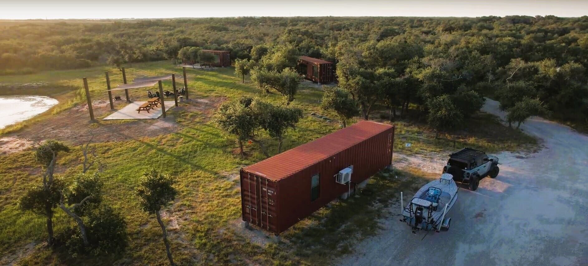 Una cabana allunyada amb un contenidor vermell, un edifici petit i un camí rural.
