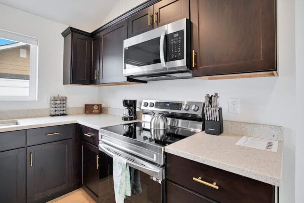 A modern kitchen with dark wood cabinets, stainless steel appliances, and a granite countertop.