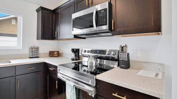 A modern kitchen with dark wood cabinets, stainless steel appliances, and a granite countertop.