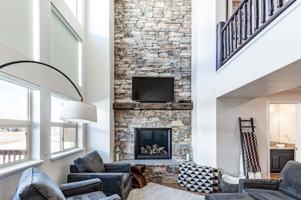 The two-story living room boasts abundant natural light, a welcoming fireplace, and Smart TV.