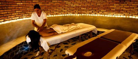 Un cuarto de spa con pared de ladrillo, una camilla de masaje y un sillón de masajes.