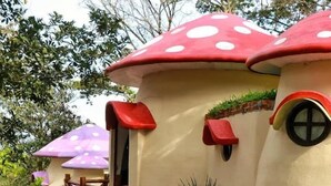 Un edificio peculiar con techos en forma de hongo y una escalera de madera que lleva a una puerta roja.
