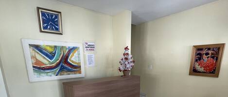 A reception area with a wooden reception desk, a clock, and two framed artworks on the walls.