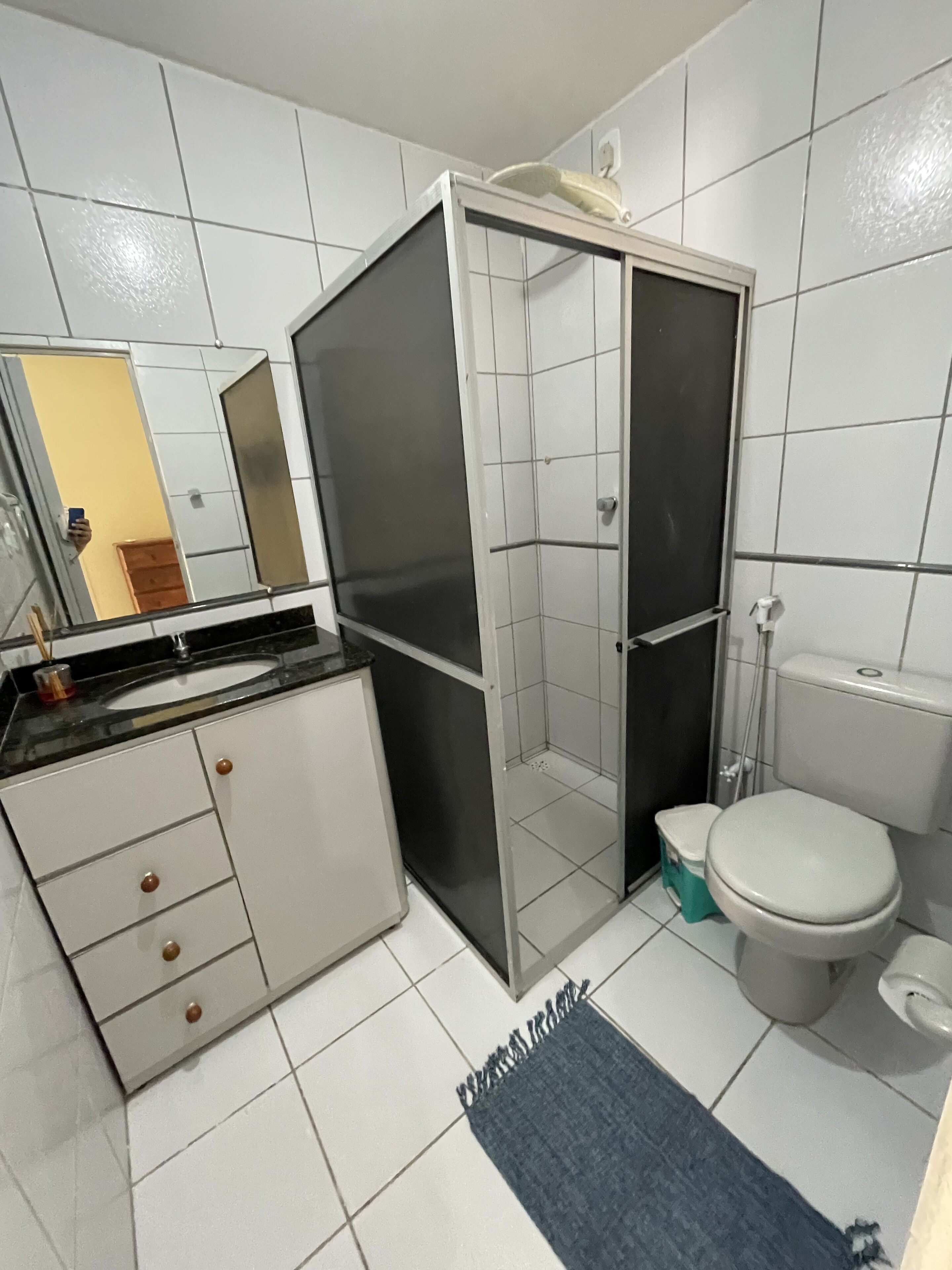 A bathroom with a shower enclosure, toilet, sink, and cabinet.