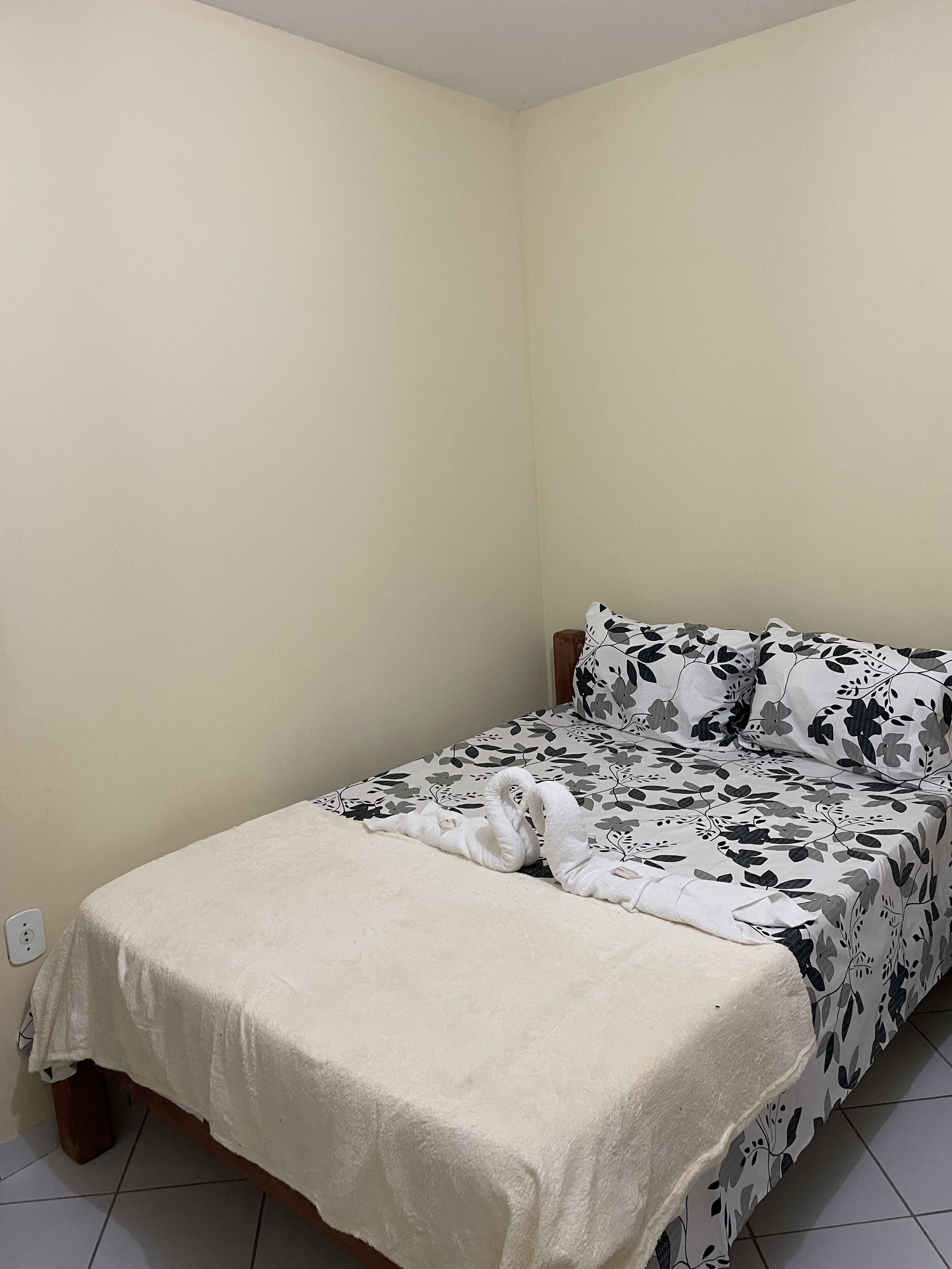 Una cama individual con un edredón estampado de flores y una manta blanca.
