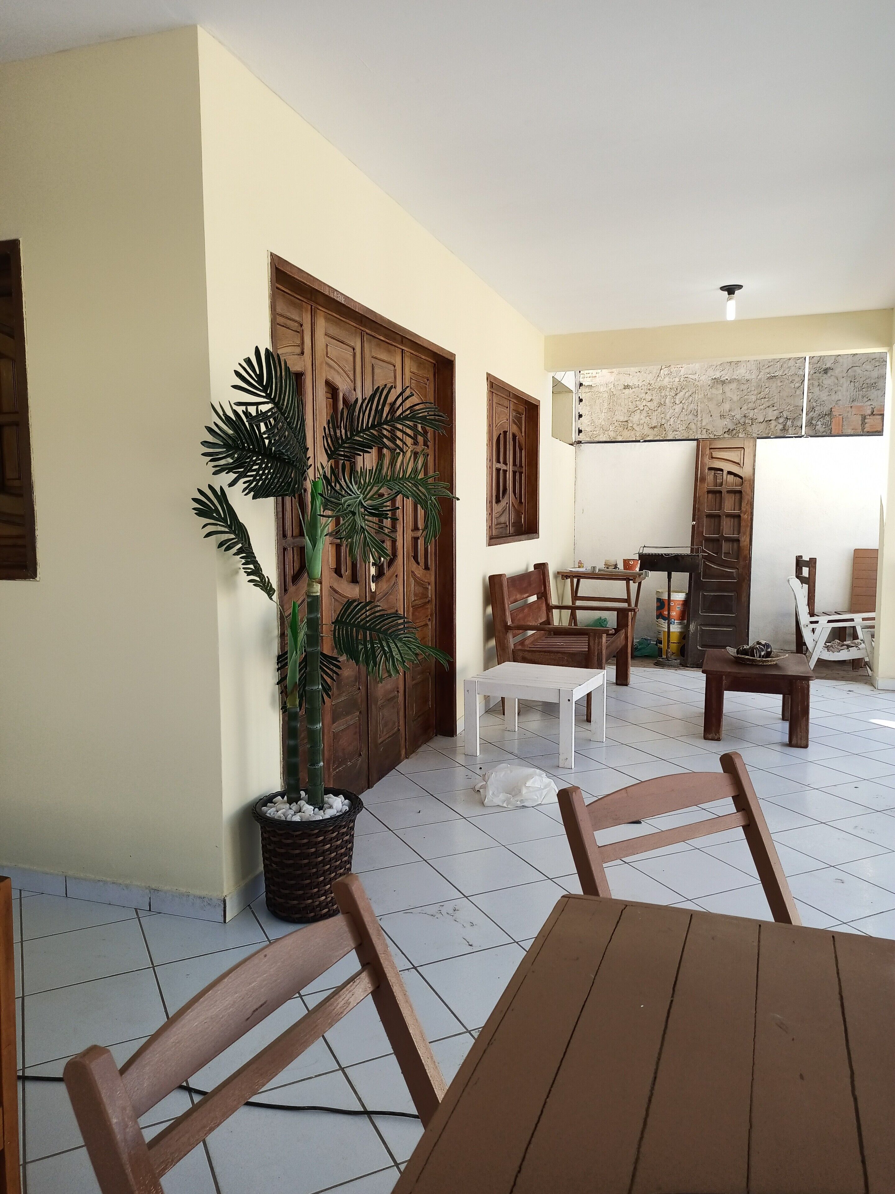 Um quarto com piso de azulejos, móveis de madeira, uma planta em vaso e uma porta com janela.