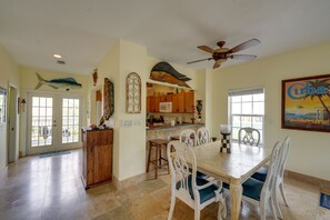 A spacious kitchen with wooden cabinets, a dining area with white chairs, and a ceiling fan.