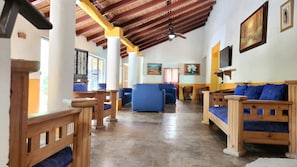 Una stanza spaziosa con panche e divani in legno, pavimento piastrellato e soffitto alto con travi a vista.
