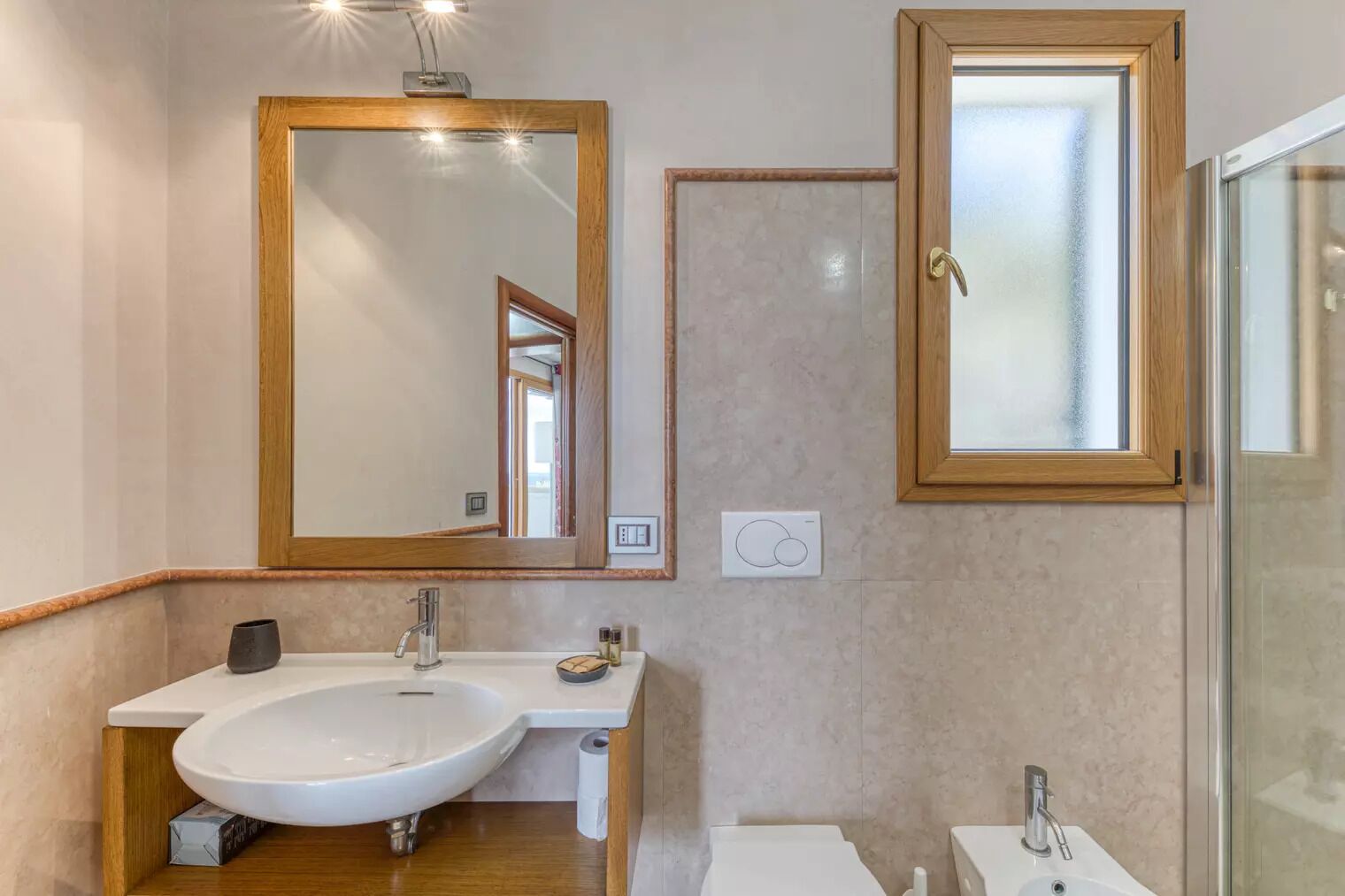 Un baño moderno con un espejo grande, un lavabo y una zona de ducha.