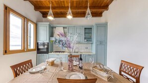 A dining area with a table set for four, wooden chairs, a kitchen in the background, and pendant lights. - SUITE VISTA MARE (Santa Cesarea Terme)