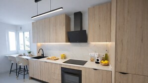 Eine moderne Küche mit Holzausbau, einer schwarzen Dunstabzugshaube, einem integrierten Geschirrspüler und einem Fenster für natürliches Licht.
