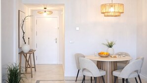 Ein zeitgemäßer Essbereich mit einem runden Tisch, vier Stühlen, einer dekorativen Lampe und einer Vase mit Blumen.