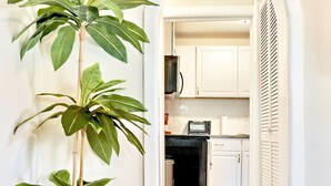 A hallway leading to a kitchen with white cabinets, a microwave, and a potted plant. - Private Birmingham Retreat Near Red Mountain Park!

 (Birmingham)