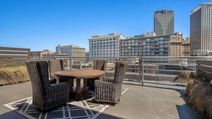 Une terrasse sur le toit, aménagée avec des meubles en osier et offrant une vue sur les bâtiments de la ville.