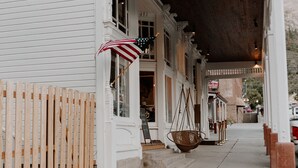 A white building with a covered porch and a wooden fence. - New Luxury Home in the Heart of Ouray, Walk Main St, Breathtaking Views, AC (Ouray)