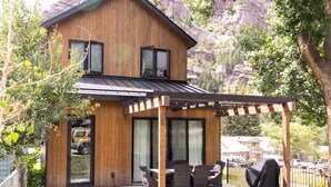 A modern two-story house with a patio area featuring outdoor furniture and a barbecue grill. - New Luxury Home in the Heart of Ouray, Walk Main St, Breathtaking Views, AC (Ouray)
