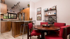 A kitchen with wooden cabinets, a central island, and a dining area with red chairs.