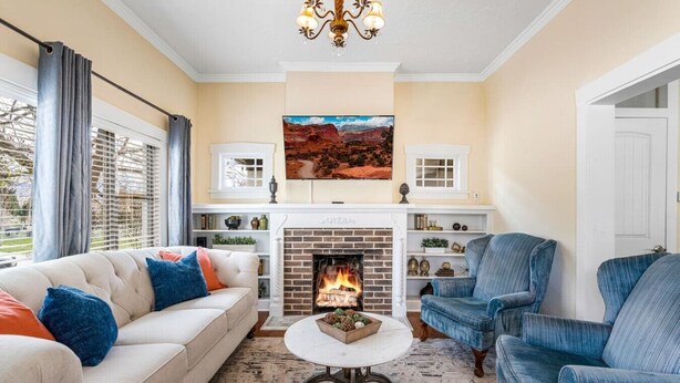 A living room with a fireplace, a sofa, a coffee table, and a blue armchair. - Quiet Home Near Downtown + Mountain Views (Salt Lake City)