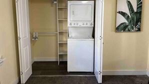 A compact room with a built-in washer and dryer, a shelving unit, and a door leading to another area. - Quiet Home Near Downtown + Mountain Views (Salt Lake City)