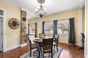 A dining area with a brick wall, a large clock, and a chandelier. - Quiet Home Near Downtown + Mountain Views (Salt Lake City)