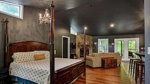 Een ruime slaapkamer met een groot bed, een kroonluchter en een stenen open haard.